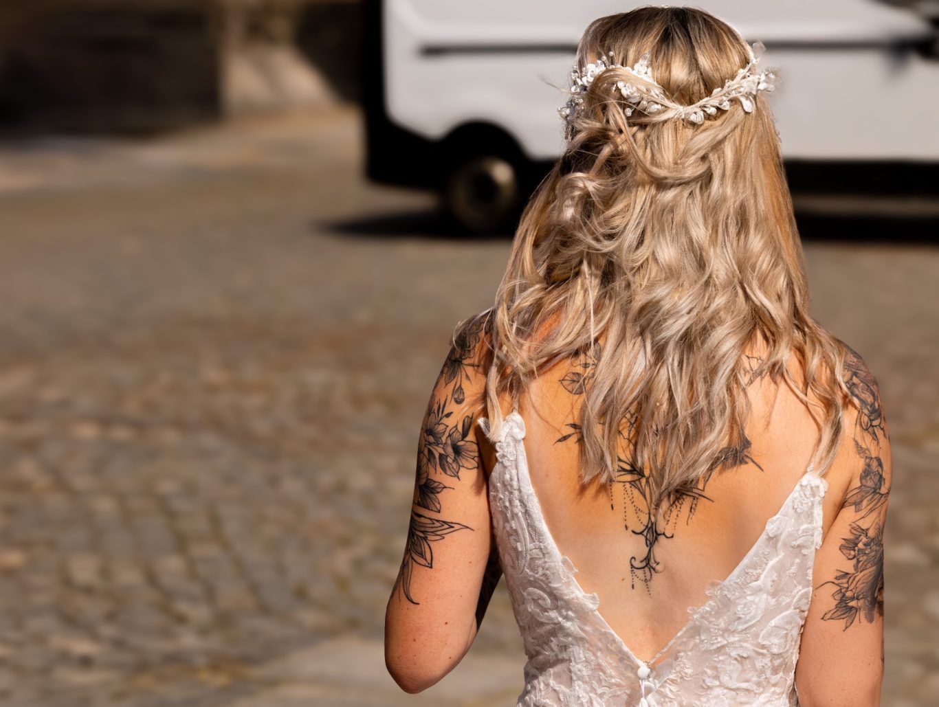 Braut Braut mit langen blonden Haaren und aufwendigen Rückentattoos in einem Spitzenkleid.
