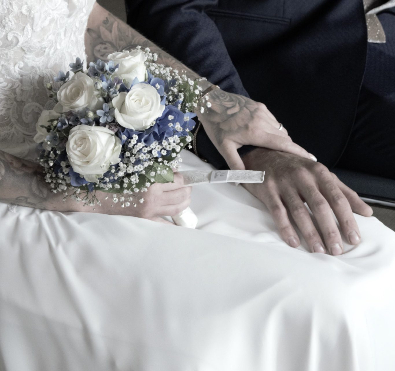 Hochzeit Braut hält einen Blumenstrauß neben der Hand des Bräutigams im Hochzeitskleid.